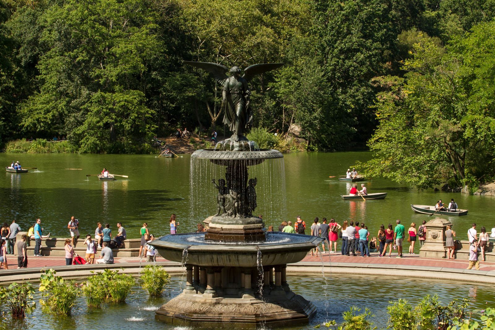 Bethesda Fountain in Central Park, with visitors around the basin and rowboats on the lake behind