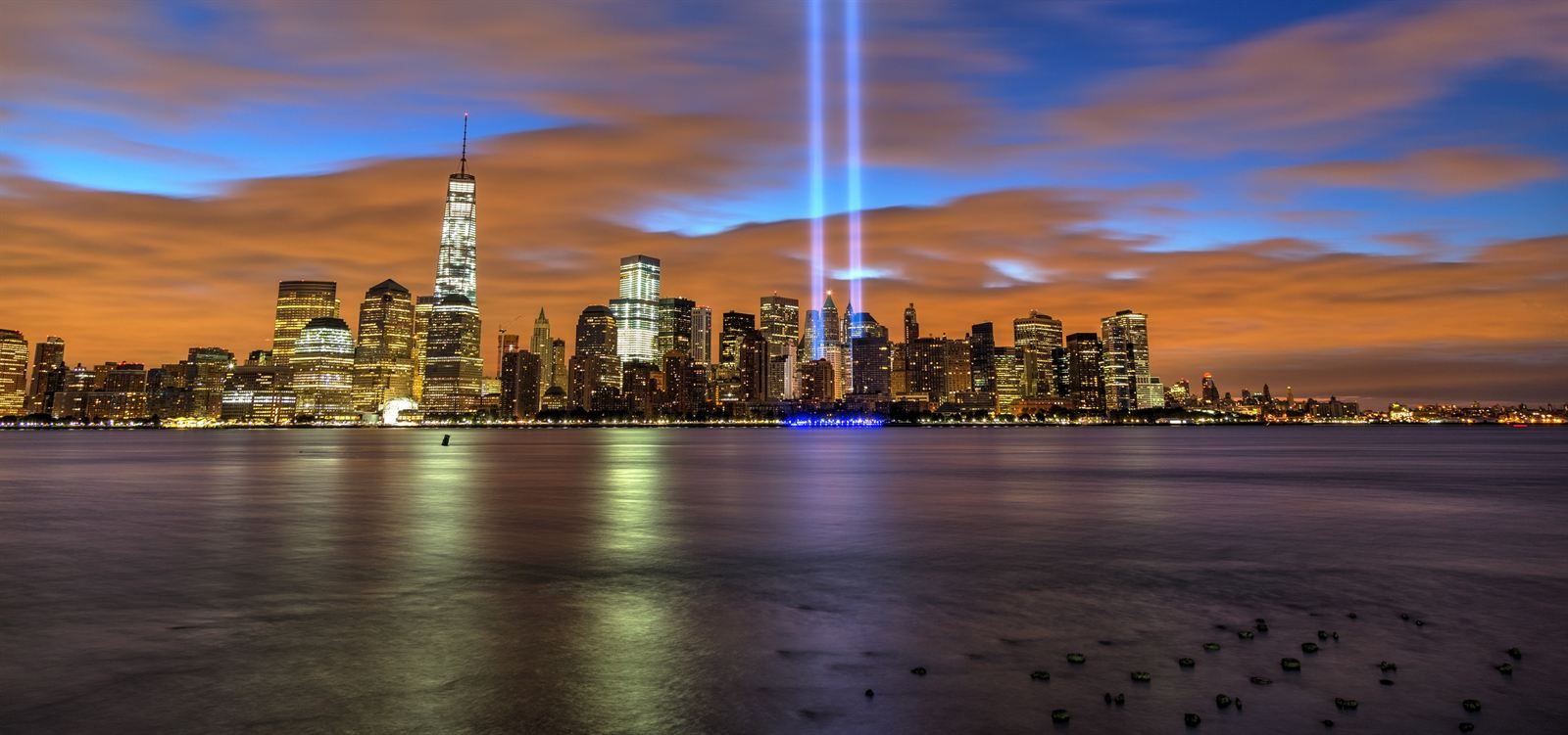 The Lower Manhattan skyline at dusk, with the twin beams of the Tribute in Light rising into the sky